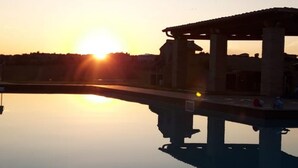 Una puesta de sol tranquila sobre una piscina serena con una estructura de quiosco.