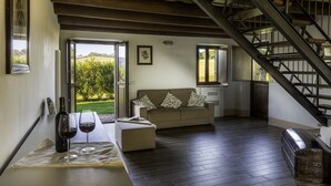 Una sala de estar acogedora con un sofá, una mesa con copas de vino y una escalera.