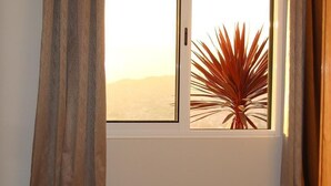 Una habitación con una cama, una ventana con cortinas y una planta.