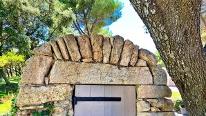 A stone archway with a wooden door, number 1749, leading to a garden area.