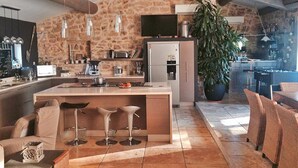 A modern kitchen with a stone wall, a large island with bar stools, and a dining area with wicker furniture.
