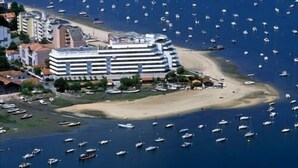 Ein Küstenhotel mit direktem Strandzugang, zahlreichen Booten im Wasser und einem Yachthafen.