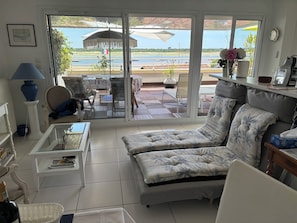 A living room with a sofa, coffee table, and a view of a patio with outdoor furniture.