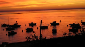 Ein Sonnenuntergang über ruhigem Wasser, mehrere Boote liegen festgemacht.