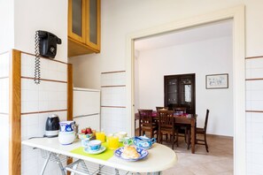 Una cocina con una mesa para el desayuno, que incluye cruasanes, fruta y jugo de naranja.