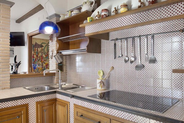 A kitchen with a tiled backsplash, wooden cabinets, and a hanging pot rack.