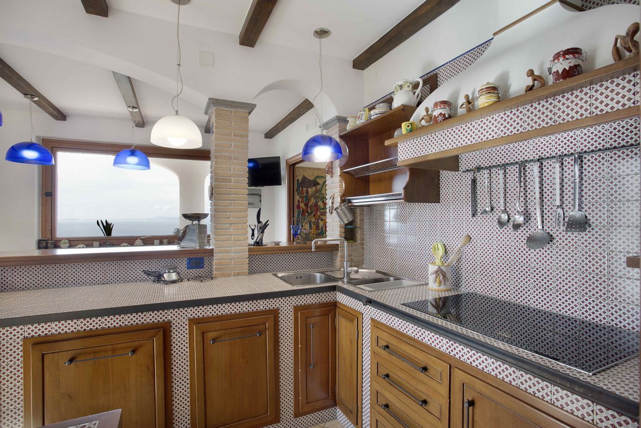Cocina con armarios de madera, un pilar de ladrillo y un salpicadero con diseño.