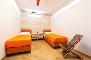 A small, brightly lit room with two beds, a wooden sculpture, and a window.