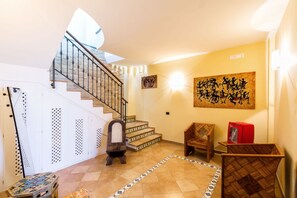A staircase leading to an upper floor, a wall-mounted artwork, and a red Coca-Cola cooler.