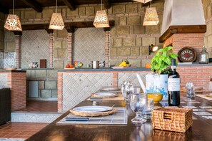 Una cocina rústica con pared de ladrillo, lámparas colgantes y una mesa de madera lista para comer.