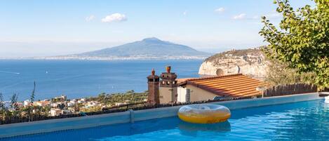 A swimming pool with a view of the sea and a mountain in the background.