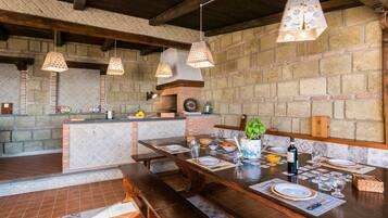 Un'accogliente sala da pranzo in stile rustico, con parete in mattoni, travi in legno e lampade a sospensione.