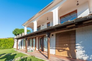 A two-story building with a covered patio and a wooden deck.