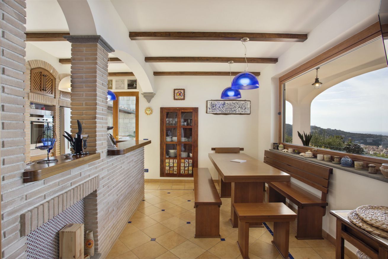 A kitchen with a brick wall, wooden beams, and a large window overlooking a cityscape.