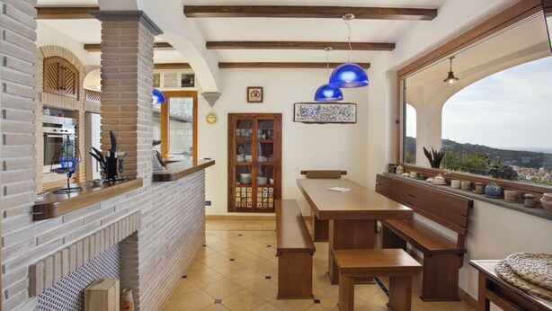 A kitchen with a brick wall, wooden beams, and a large window overlooking a cityscape.
