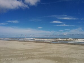 Une plage avec un ciel dégagé et des vagues.