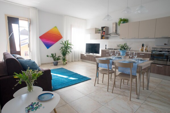 A modern living room with a sofa, coffee table, and a dining area with chairs and a table set for two.