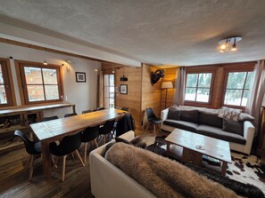 A cozy cabin interior with a wooden dining table, a sofa, and a lamp.