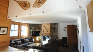 A cozy living room with a stone fireplace, wooden beams, and a large window. - Typical chalet, combining the charm of wood and stone, overlooking the Isère river  (Tignes)