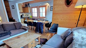 A cozy living room with a sofa, a coffee table, and a mounted ram head decoration. - Typical chalet, combining the charm of wood and stone, overlooking the Isère river  (Tignes)