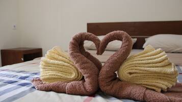 A bed with a checkered bedspread and two swan-shaped towels made of brown and yellow fabric.