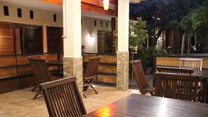 Ein Außenbereich mit einer Terrasse, Holztafeln und -stühlen, Steinpfeilern und einer Ziegelwand.
