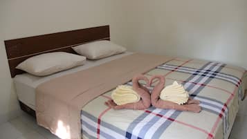 A neatly made bed with a checkered bedspread, two heart-shaped towels, and a beige blanket.