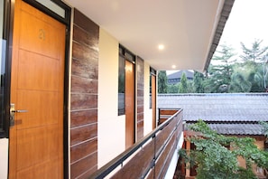 A modern building with wooden doors and a balcony overlooking a garden.