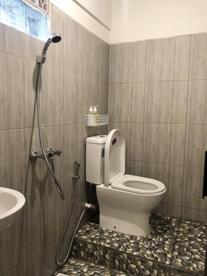 A bathroom with a toilet, shower, and sink.