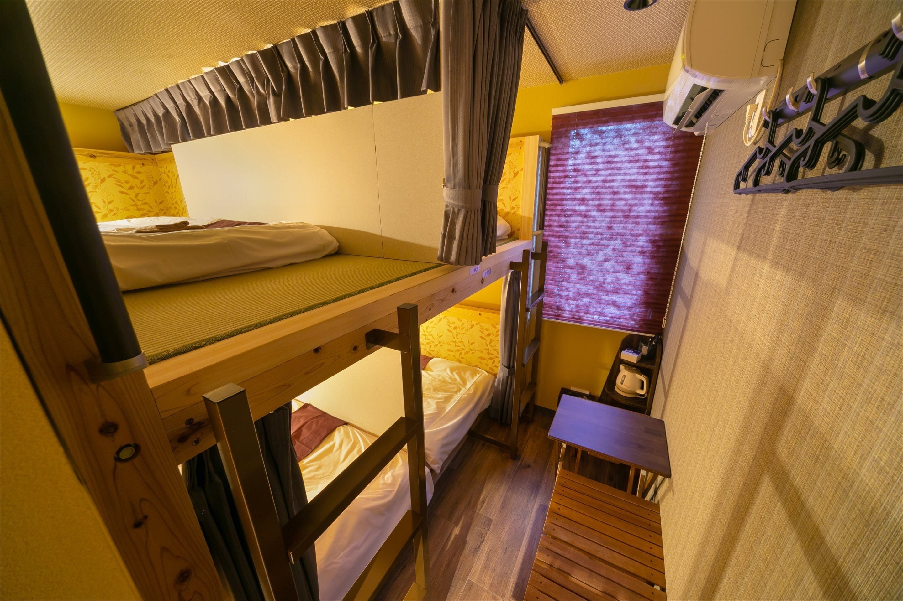 A compact room with bunk beds, a small table, and a window with curtains.