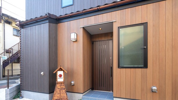 Een modern gebouw met een houten gevel, een glazen deur en een klein houten bordje.