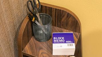 Une étagère en bois avec une paire de ciseaux, un récipient perforé et un bloc-notes marqué « BLOCK MEMO 400 ».