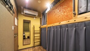 Een hotelkamer met een houten vloer, een spiegel, een houten deur en een raam met gordijnen.
