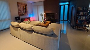 Ein modernes Wohnzimmer mit einer Couch, einem Flachbildfernseher, einem Bücherregal und einem Bild an der Wand.