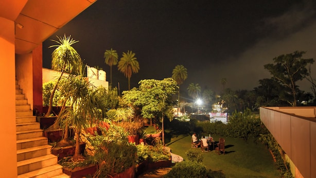 A well-lit outdoor area with a staircase, potted plants, and a seating area with people. - Hotel Dev Residency (Abu Road)