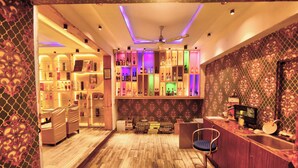 A bar area with wooden flooring, a ceiling fan, and shelves stocked with bottles. - Hotel Dev Residency (Abu Road)