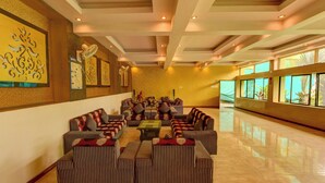 A spacious lobby with a central seating area featuring striped sofas and armchairs, a fan, and artwork on the walls. - Hotel Dev Residency (Abu Road)