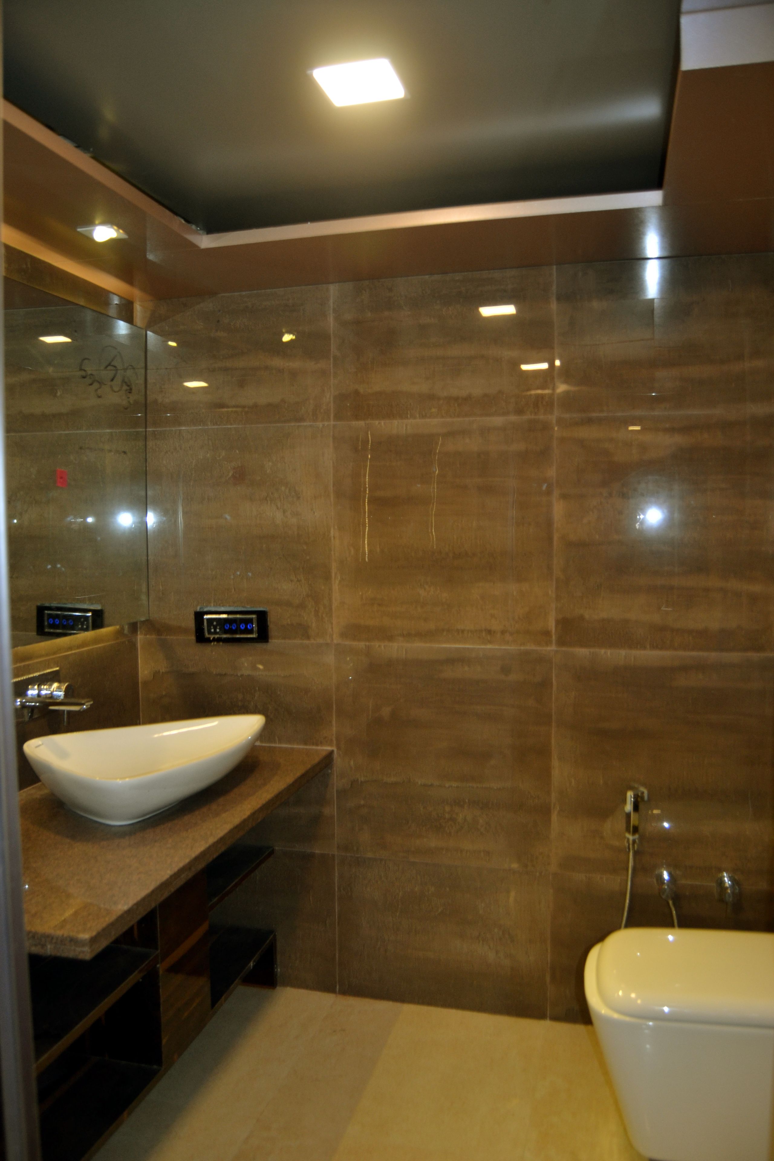 Un baño moderno con un espejo grande, un lavabo blanco y un inodoro.