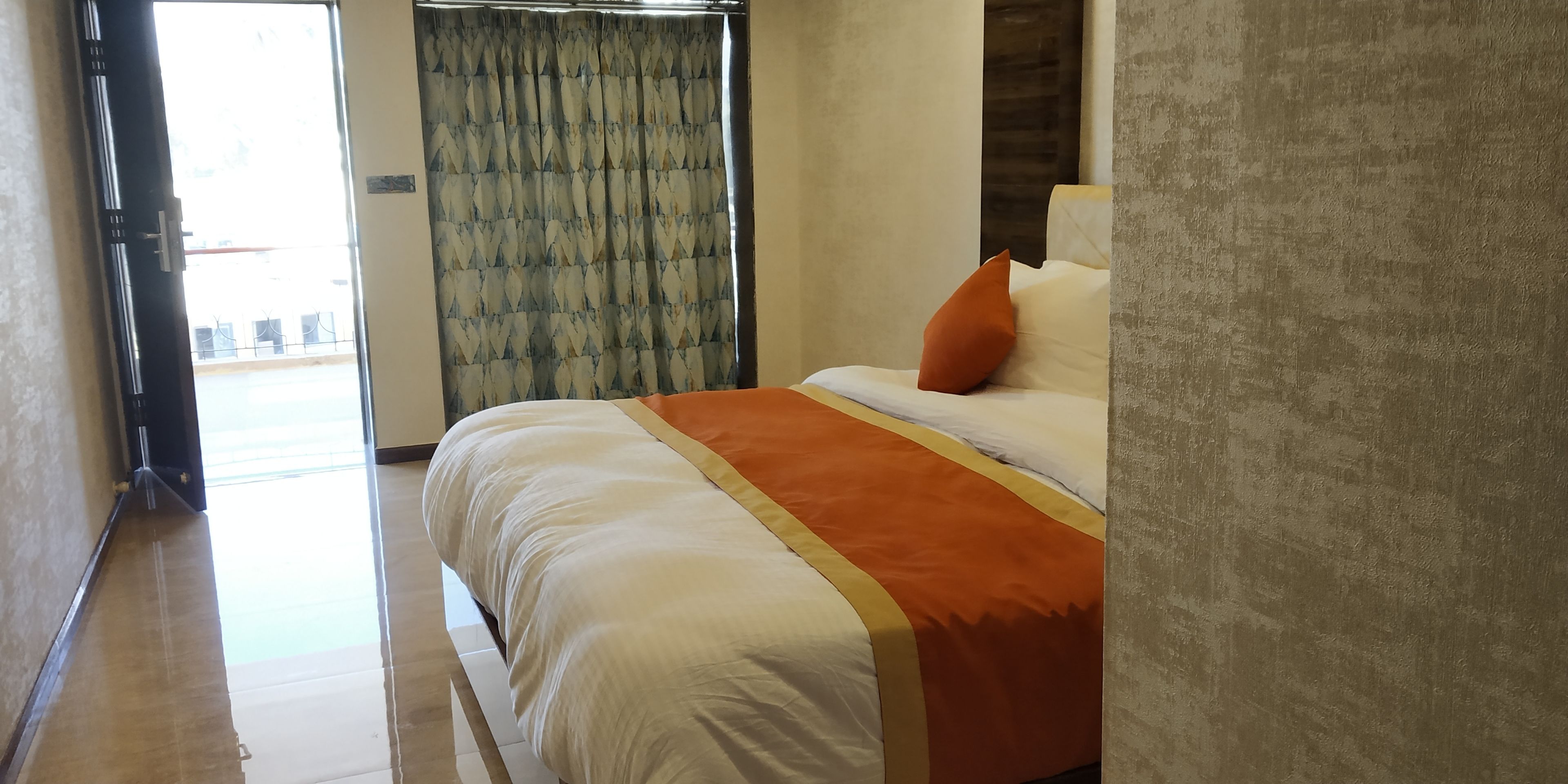 Une chambre d’hôtel avec un lit, un rideau et une vue à travers une porte.
