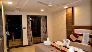 A hotel room with a bed, curtains, a ceiling fan, and a view through a glass door. - Hotel Dev Residency (Abu Road)