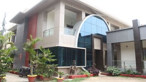 A modern building with a large glass facade, a curved entrance, and a red and grey color scheme. - Hotel Dev Residency (Abu Road)