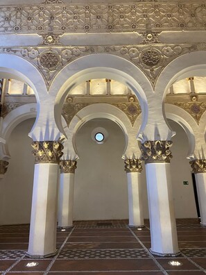 Un intérieur caractérisé par des arches et des colonnes, un sol à motifs et une fenêtre circulaire centrale.