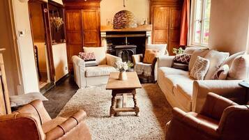 Een gezellige woonkamer met een open haard, houten meubels en een vloerkleed.