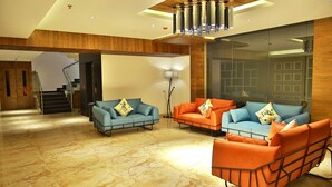 A modern lobby with a marble floor, two sofas with colorful cushions, a standing lamp, and a staircase leading to another area. - Casa Montana (Devikolam)