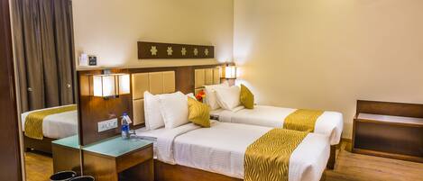 A hotel room with a large bed, a desk, a mirror, and a ceiling fan.