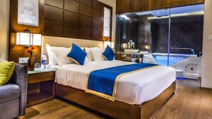 A modern hotel room with a large bed, a glass-enclosed jacuzzi, and a view of the city. - Casa Montana (Devikolam)