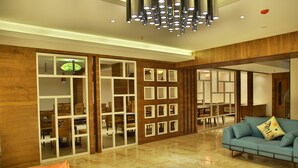 A modern living room with a blue sofa, wooden panel walls, and a marble floor. - Casa Montana (Devikolam)