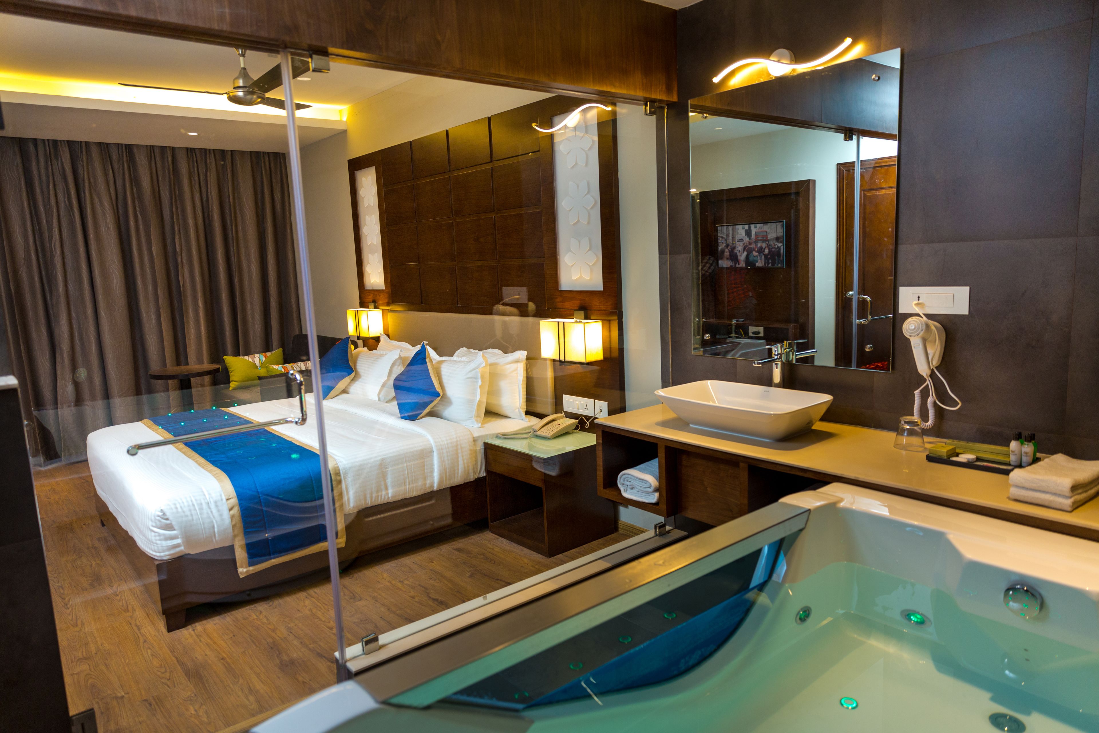 Une chambre d’hôtel avec un lit, une table de chevet, une lampe et un grand miroir.
