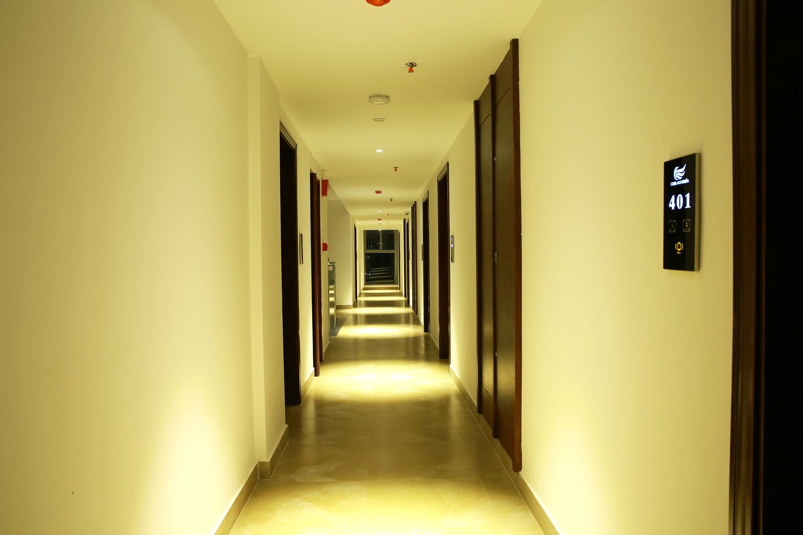 A long, well-lit hallway with doors on both sides, leading to multiple rooms.