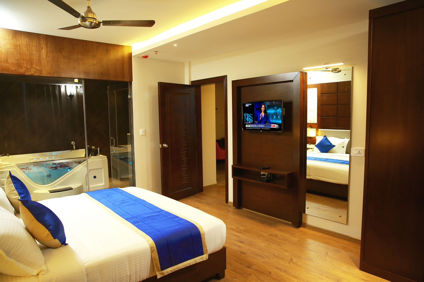 Habitació d'hotel amb un llit, televisió, banyera de massatge i una porta que condueix a una altra habitació.